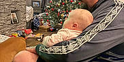 Willow is registered to the contest to win money with this photo: baby, casual_clothing, child, christmas_tree, curtains, dog, family, furniture, glasses, holiday_decorations, indoor, living_room, man, ornaments, person, photo_frame, seated, sports, stone_wall, television