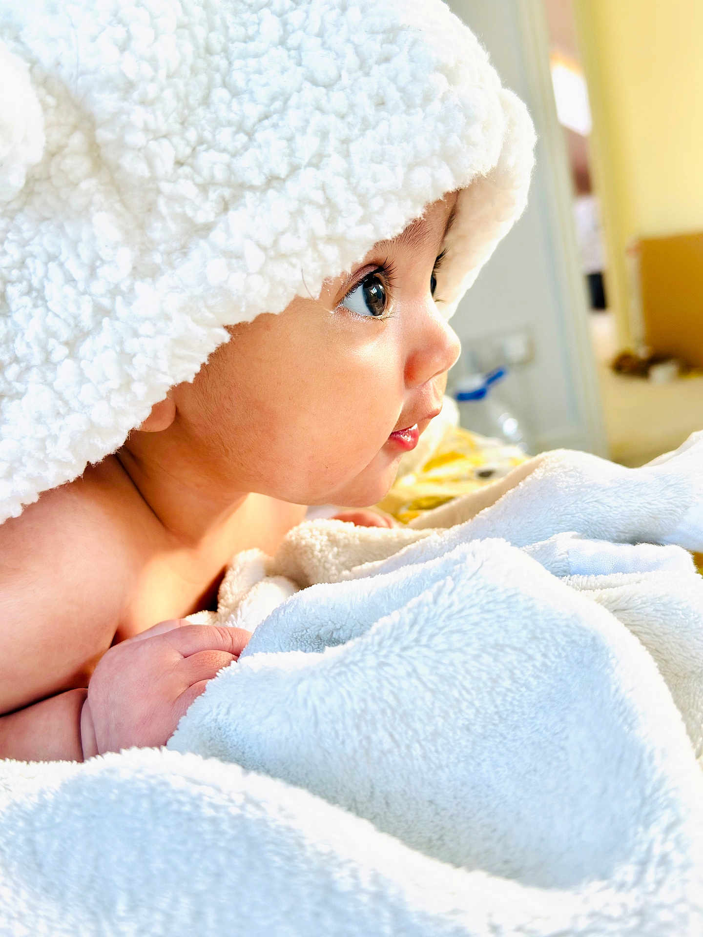 Alyana is registered to the contest to win money with this photo: baby, blanket, face, hand, soft_texture, curious, indoors, closeup, child, skin, cozy, cute, portrait, expression, infant, toddler, white, warm, comfort, sleepwear