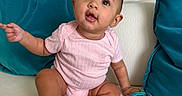 Katalina is registered to the contest to win money with this photo: baby, barefoot, child, couch, curious, cute, expression, face, furniture, home, indoors, infant, person, pink_onesie, pointing, portrait, sitting, sofa, teal_cushions, young