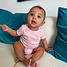 Katalina is registered to the contest to win money with this photo: baby, child, infant, pink_onesie, couch, sofa, teal_cushions, pointing, curious, indoors, expression, face, person, sitting, barefoot, home, furniture, cute, portrait, young