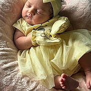 Elianna joined the competition — help win amazing prizes! baby, sleeping, yellow_clothing, headband, mittens, blanket, soft_texture, infant, peaceful, cute, newborn, portrait, indoors, tulle_skirt, foot, hand, resting, cozy, child, adorable