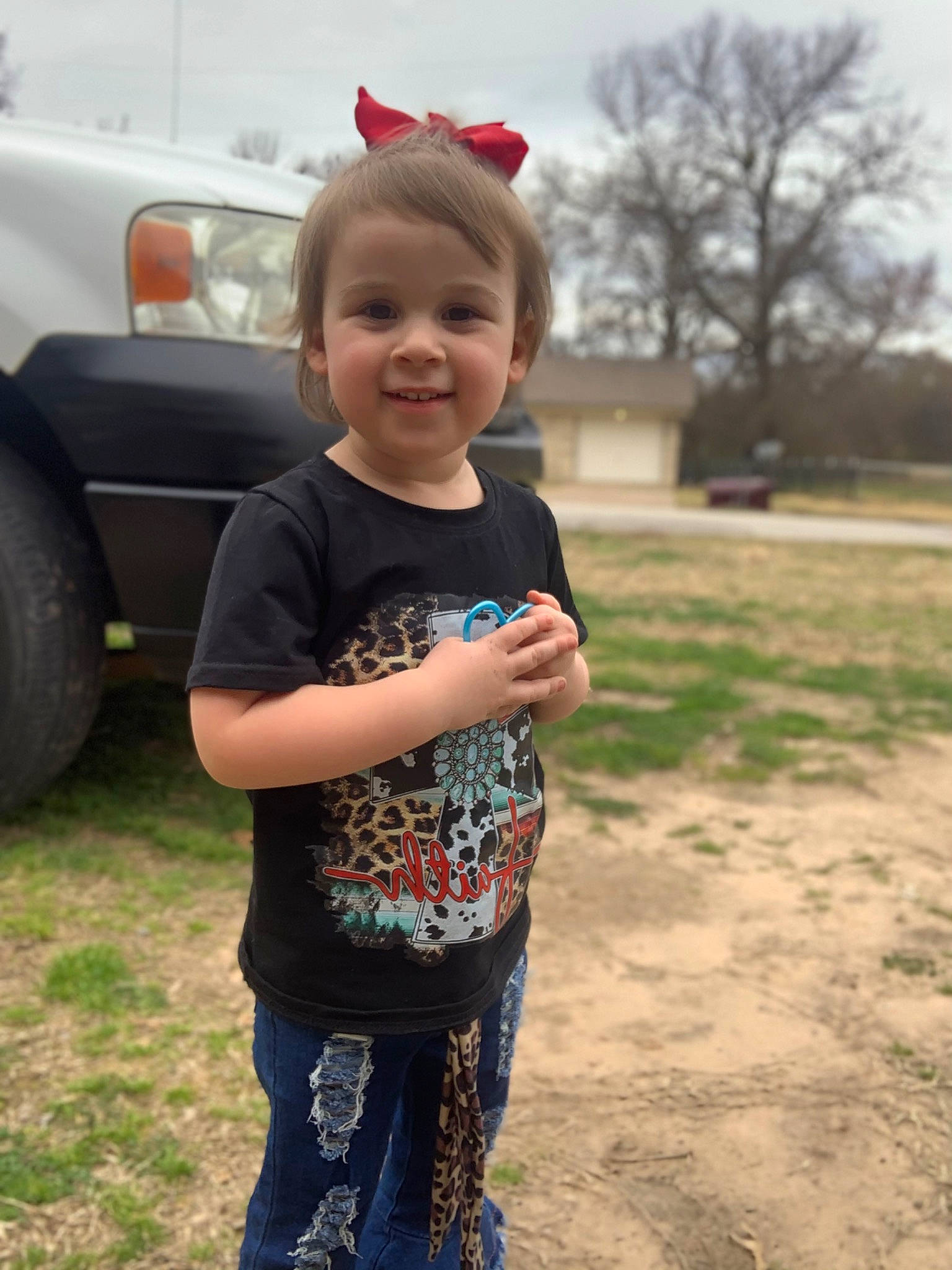 Peyton is registered to the contest to win money with this photo: asphalt, automotive_exterior, automotive_lighting, automotive_tire, car, cool, grass, happy, joy, mammal, person, plant, sky, smile, summer, t_shirt, tire, toddler, tree, vehicle