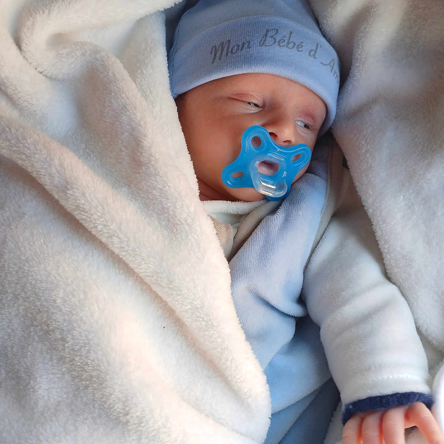 Kayron a rejoint le concours — aidez-le/la à gagner de superbes lots ! baby, blanket, blue_hat, blue_pacifier, child, clothing, cozy, face, hand, infant, newborn, pacifier, person, sleepy, soft, toddler, wearing, white_blanket, wrapped, young_child