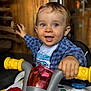 Clark participe au concours pour gagner de l'argent avec cette photo : toddler, child, smiling, toy, vehicle, yellow_handles, blue_shirt, plaid_shirt, indoor, wooden_background, happy, face, hands, playful, closeup, cute, person, young_child, expression, fun
