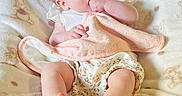 Audrey is registered to the contest to win money with this photo: baby, infant, blanket, soft_texture, teddy_bear_pattern, clothing, white_top, floral_shorts, hand_in_mouth, pink_cloth, barefoot, cute, child, portrait, indoors, relaxed, lying_down, bright_eyes, skin, comfort