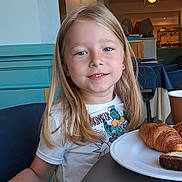 Antonio a rejoint le concours — aidez-le/la à gagner de superbes lots ! blonde_hair, bracelet, breakfast, cafe, cake, chair, child, croissant, dining, food, furniture, happy, indoor, light, person, plate, portrait, smile, table, tshirt
