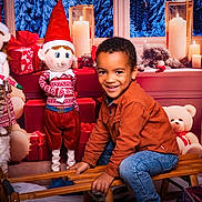 Benjamin a rejoint le concours — aidez-le/la à gagner de superbes lots ! child, smiling_child, christmas, elf_doll, stuffed_toy, teddy_bear, gifts, present, sled, holiday_backdrop, candle, window, red_decor, basket, jeans, brown_jacket, indoor, festive_scene, portrait, smile