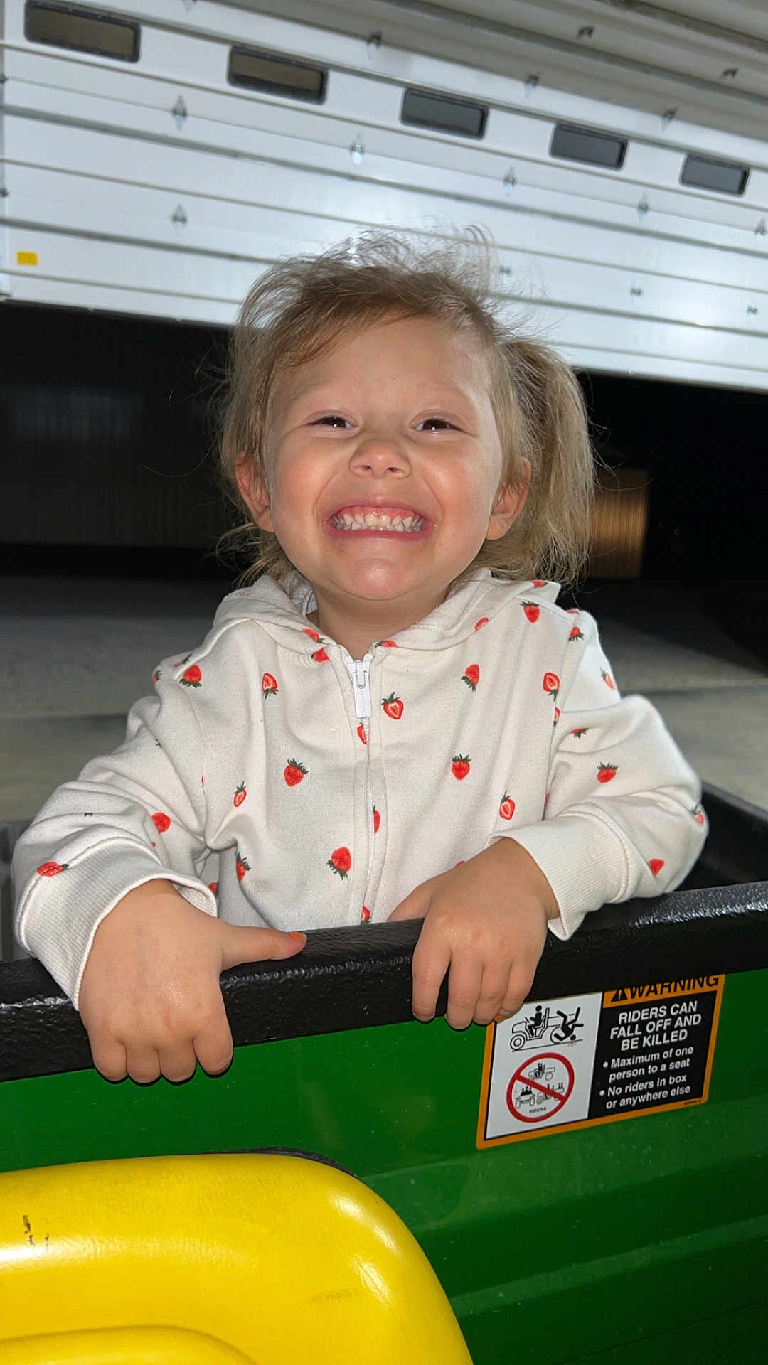 Sophia joined the competition — help win amazing prizes! child, smiling, hoodie, strawberry_pattern, hands, vehicle, green, yellow, garage_door, night, happy, person, casual_clothing, outdoor, portrait, cute, holding, joyful, young, face