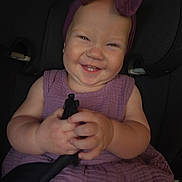 Alruna joined the competition — help win amazing prizes! baby, child, smile, headband, purple, dress, car_seat, seatbelt, hands, happy, cute, infant, chubby_cheeks, portrait, indoors, person, clothing, holding, young, face