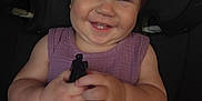 Alruna is registered to the contest to win money with this photo: baby, car_seat, child, chubby_cheeks, clothing, cute, dress, face, hands, happy, headband, holding, indoors, infant, person, portrait, purple, seatbelt, smile, young