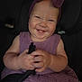 baby, child, smile, headband, purple, dress, car_seat, seatbelt, hands, happy, cute, infant, chubby_cheeks, portrait, indoors, person, clothing, holding, young, face