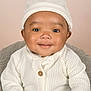 baby, infant, smile, white_sweater, knit_hat, cute, portrait, child, face, happy, warm_clothing, indoor, soft_lighting, cozy, young_child, close_up, headwear, buttoned_sweater, neutral_background, adorable