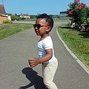 Vincent Uriel participe au concours pour gagner de l'argent avec cette photo : beige_pants, child, cute, flowers, grass, outdoor, path, pavement, profile, residential_area, sandals, shadow, sidewalk, sky, smile, sunglasses, sunny, toddler, walking, white_shirt