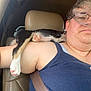 Angel is registered to the contest to win money with this photo: person, dog, puppy, car_interior, glasses, seatbelt, tank_top, headrest, paw, window, seat, short_hair, casual_clothing, closeup, relaxing, indoor, seatbelt_fastened, resting, animal, pet