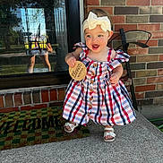 Mckenzie joined the competition — help win amazing prizes! baby, child, girl, dress, headband, bow, plaid, sandals, porch, concrete, brick_wall, reflection, door, glass, welcome_mat, outdoor, smiling, holding, months_sign, happy