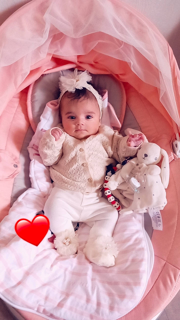 Kataleya participe au concours pour gagner de l'argent avec cette photo : baby, baby_toddler_clothing, cheek, child, comfort, dress, facial_expression, hand, happy, head, human, mammal, outerwear, person, pink, red, skin, sleeve, textile, toddler