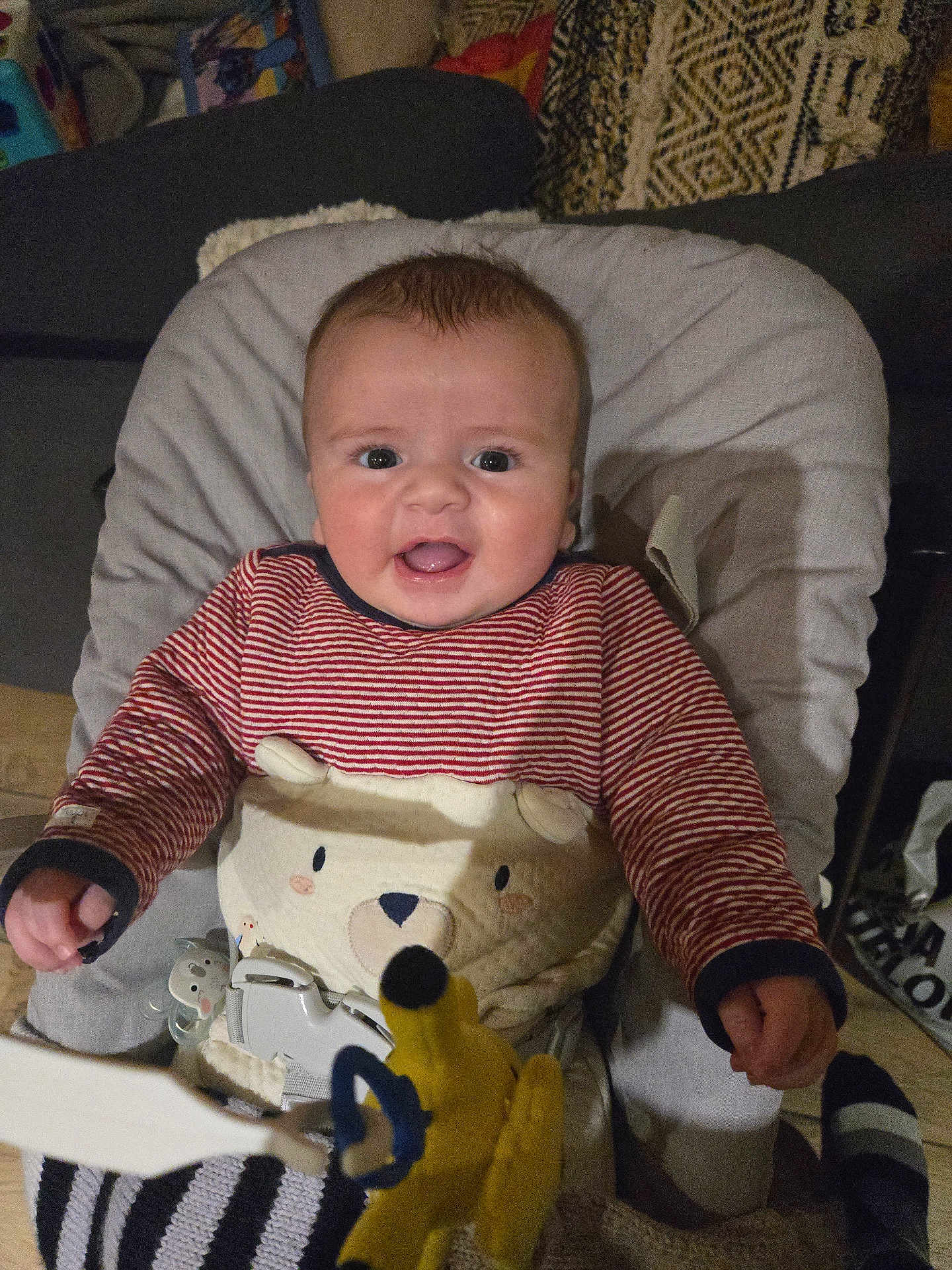 Antoine participe au concours pour gagner de l'argent avec cette photo : baby, baby_chair, bear_design, child, cozy, cushion, cute, face, hand, happy, home, indoor, infant, person, plush_toy, seated, smiling, striped_clothing, warm_lighting, yellow_toy