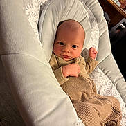 Sebastian is registered to the contest to win money with this photo: baby, infant, onesie, baby_seat, cushion, animal_print, face, eyes, hand, wooden_furniture, flowers, blanket, indoor, portrait, newborn, cozy, soft_fabric, child, resting, cute