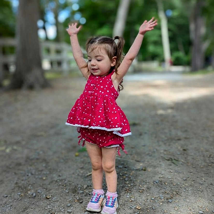 Maisie is registered to the contest to win money with this photo: child, clothing, dress, face, female, footwear, girl, grass, happy, head, nature, outdoors, park, person, photography, plant, portrait, sandal, tree, vegetation