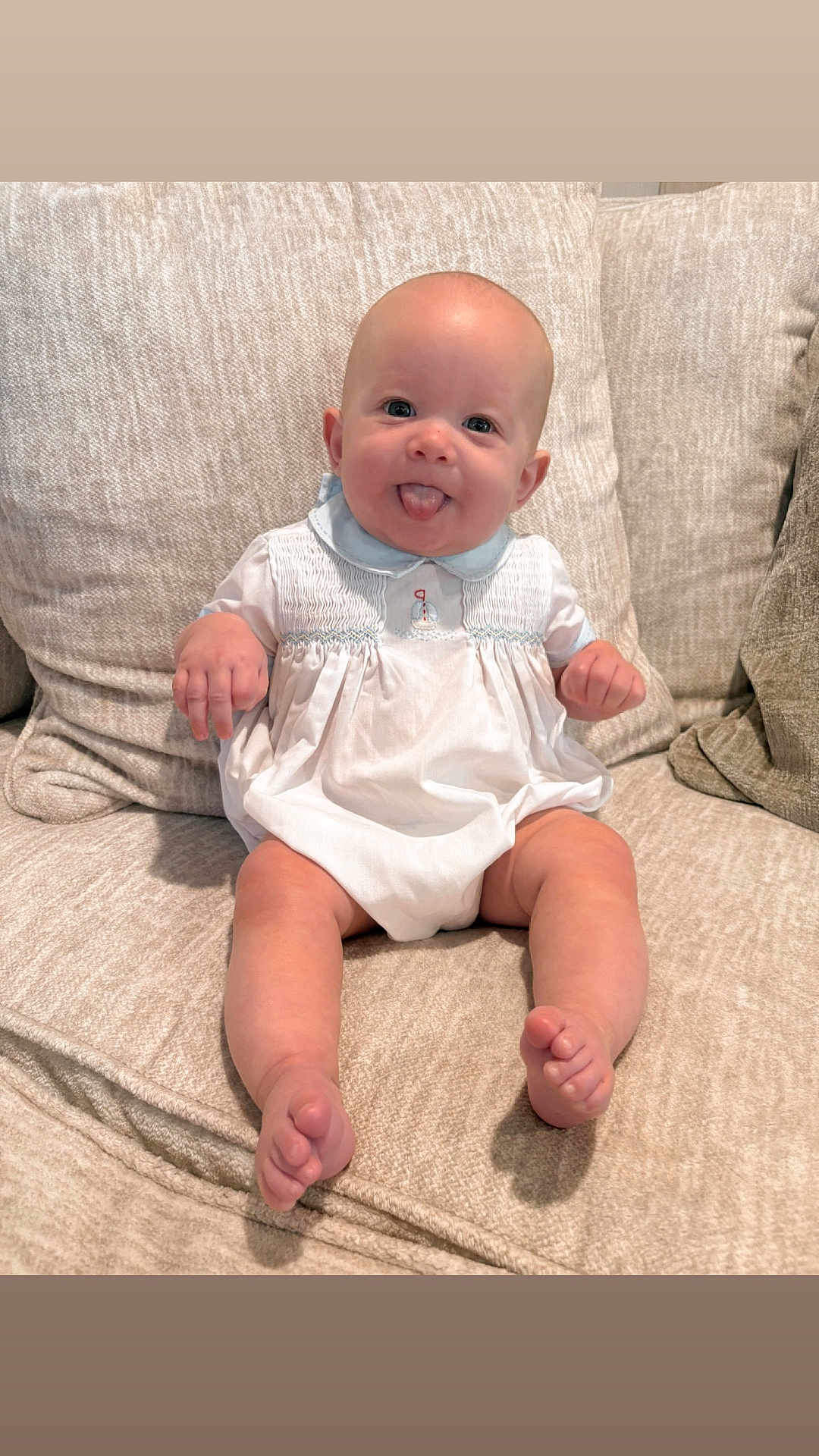 Hudson joined the competition — help win amazing prizes! baby, child, couch, sofa, cushion, infant, tongue_out, white_clothing, sitting, cute, smiling, homedecor, furniture, indoor, portrait, person, skin, head, feet, hands
