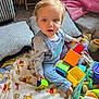 toddler, child, toys, blanket, winnie_the_pooh, indoor, playing, colorful, curious, blue_eyes, overalls, soft_toys, basket, floor, carpet, pillow, pink_blanket, cute, expression, young_child