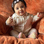 Dua joined the competition — help win amazing prizes! armchair, baby, child, cozy, cute, footwear, hair_clips, happy, indoor, infant, knitted_clothing, orange, person, plush, portrait, seated, small_hands, smiling, soft_lighting, warm_colors