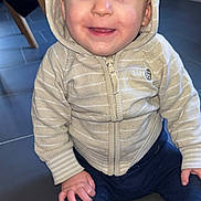 Milo participe au concours pour gagner de l'argent avec cette photo : baby, child, hoodie, striped_clothing, smiling, sitting, floor, tile, indoor, person, happy, cute, casual_wear, blue_pants, long_sleeves, young_child, portrait, bright_eyes, cozy, zipper