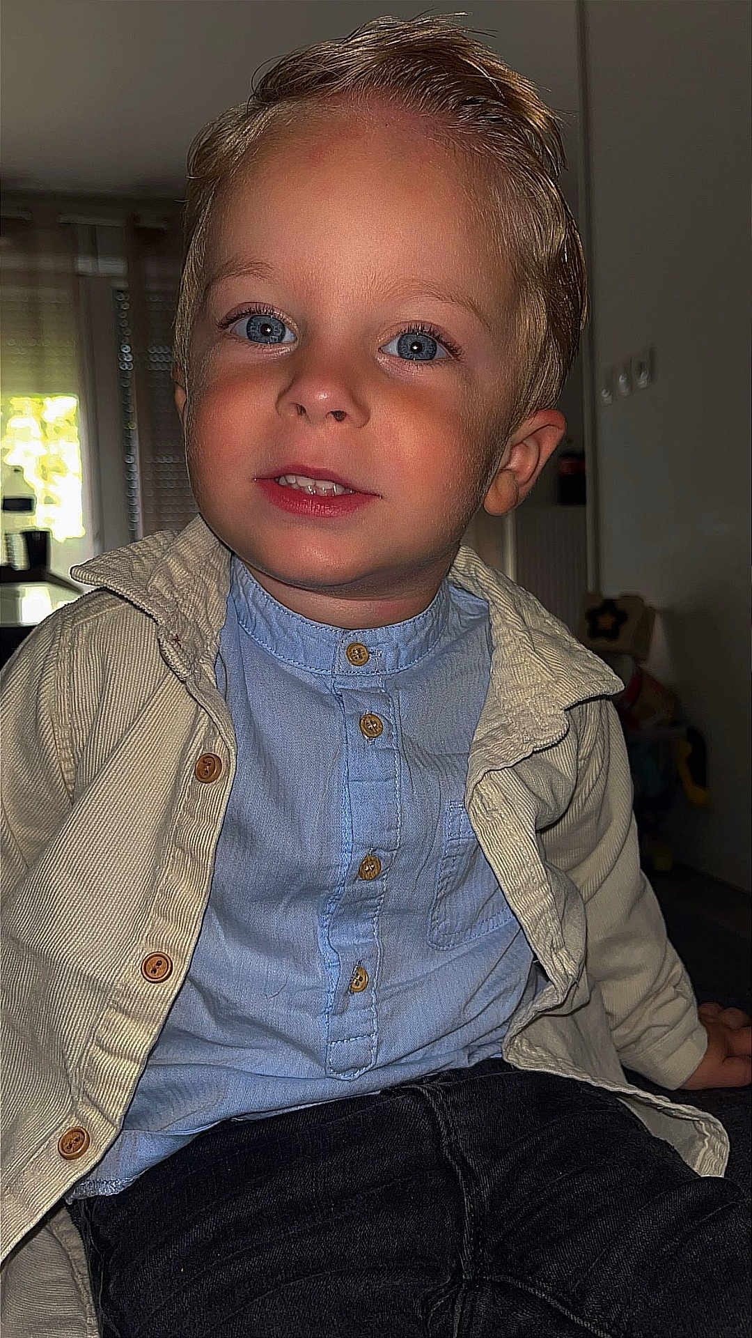 Thiago participe au concours pour gagner de l'argent avec cette photo : child, boy, portrait, indoor, blue_eyes, smile, jacket, shirt, buttons, seated, face, hair, light, window, background, furniture, young, casual_clothing, happy, person