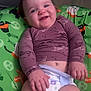 Eloise is registered to the contest to win money with this photo: baby, smiling, infant, diaper, purple_shirt, green_cushion, halloween_prints, cute, happy, child, indoor, portrait, young_child, sitting, face, hand, legs, comfort, joy, casual