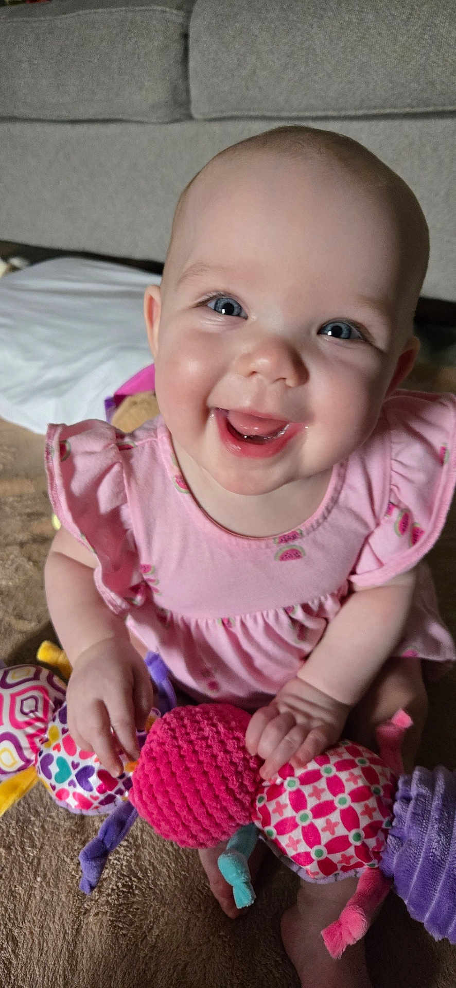 Imogen joined the competition — help win amazing prizes! baby, child, smiling, pink_dress, plush_toy, carpet, indoor, happy, cute, infant, portrait, sitting, toy, hand, face, blue_eyes, young_child, couch, person, bright