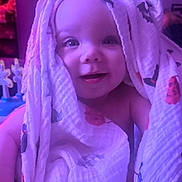 Imogen joined the competition — help win amazing prizes! baby, child, smile, blanket, cloth, indoor, purple_light, toy, face, happy, person, infant, cute, head, hand, fabric, home, decor, wrapped, playful
