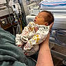newborn, baby, infant, person, hospital, medical_equipment, clothing, sleeping, arms, hand, bed, blanket, pattern, animal_print, indoor, care, healthcare, child, swaddled, peaceful