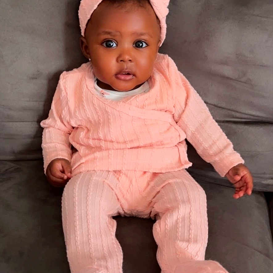 Aasani joined the competition — help win amazing prizes! baby, bodypart, bonnet, cap, clothing, couch, face, finger, furniture, hand, happy, hat, head, hood, pants, person, photography, portrait, sitting, smile