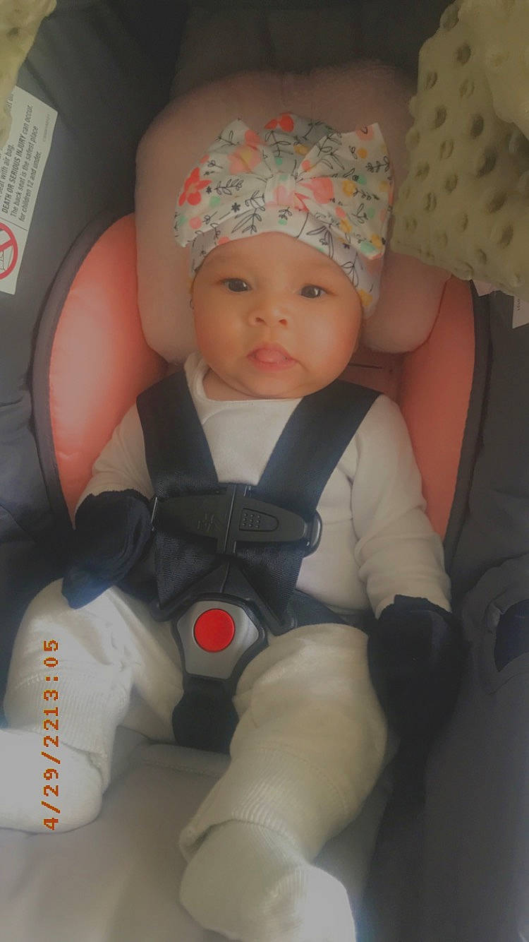 Kaia is registered to the contest to win money with this photo: auto_part, baby, baby_carriage, baby_products, baby_toddler_clothing, cap, car_seat, carmine, cheek, child, comfort, fashion_accessory, finger, headwear, knee, person, personal_protective_equipment, sitting, smile, thigh