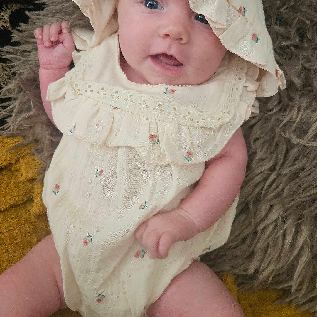 Eleanor is registered to the contest to win money with this photo: baby, bodypart, bonnet, cap, clothing, diaper, dress, face, finger, hand, happy, hat, head, hood, newborn, person, photography, portrait, smile, sunhat