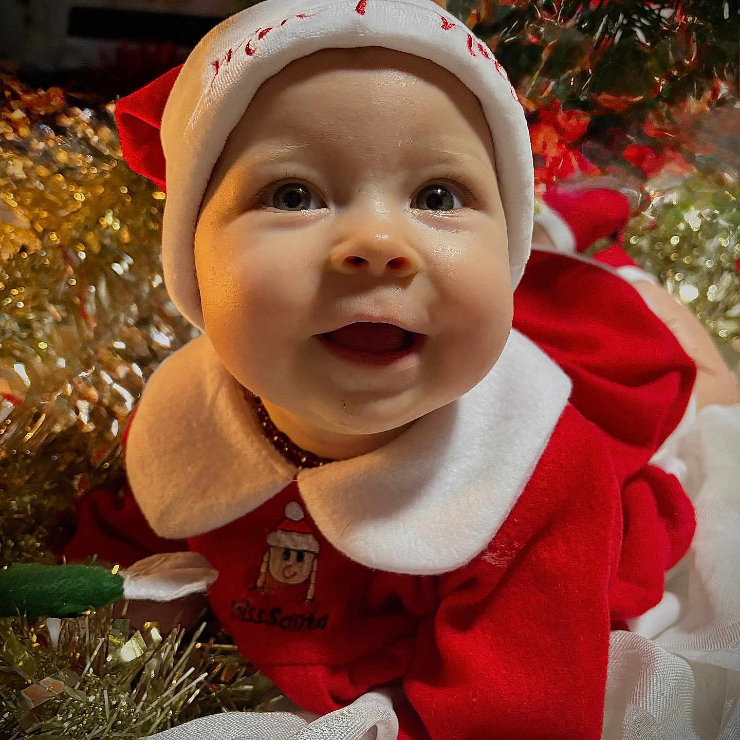 Judyth participe au concours pour gagner de l'argent avec cette photo : baby, celebration, child, christmas, closeup, cute, decorations, face, festive, happy, holiday, indoors, infant, portrait, red_clothing, santa_hat, smile, sparkle, tulle, white_collar