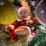 baby, child, christmas, holiday, festive, tinsel, tree, ornaments, smiling, red_clothing, socks, hat, cute, celebration, decorations, face, person, indoors, seasonal, happy
