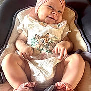 Judyth a rejoint le concours — aidez-le/la à gagner de superbes lots ! baby, smile, infant, headband, flower, pink, white_clothing, deer_print, cushion, baby_carrier, happy, cute, legs, hands, socks, soft_lighting, portrait, child, indoors, cozy