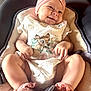 baby, smile, infant, headband, flower, pink, white_clothing, deer_print, cushion, baby_carrier, happy, cute, legs, hands, socks, soft_lighting, portrait, child, indoors, cozy
