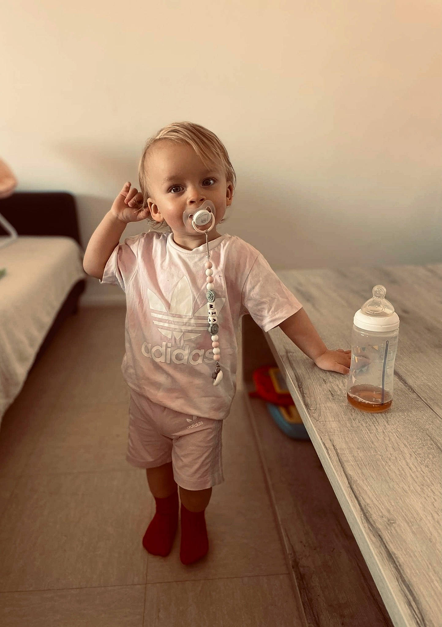 Mia a rejoint le concours — aidez-le/la à gagner de superbes lots ! baby, baby_toddler_clothing, child, floor, flooring, foot, fun, gesture, happy, hardwood, human_leg, person, room, skin, sleeve, smile, standing, t_shirt, thumb, toddler