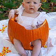 Harper joined the competition — help win amazing prizes! baby, pumpkin, candy_corn, outdoor, grass, autumn, child, white_clothing, sitting, expression, cute, festive, orange, leaf_litter, hand, foot, person, skin, head, nature