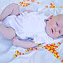 baby, infant, candy_corn, white_outfit, lying_down, soft_lighting, pale_skin, blue_eyes, chubby_arms, chubby_legs, sheet, background, indoors, cute, child, portrait, food, colorful, sweet, holiday