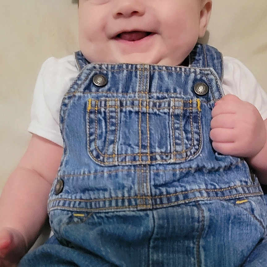 Gabriella joined the competition — help win amazing prizes! baby, background, cheeks, child, clothing, cute, denim_overalls, eyes, fabric, face, hand, happy, headband, indoors, infant, lying_down, portrait, skin, smile, soft