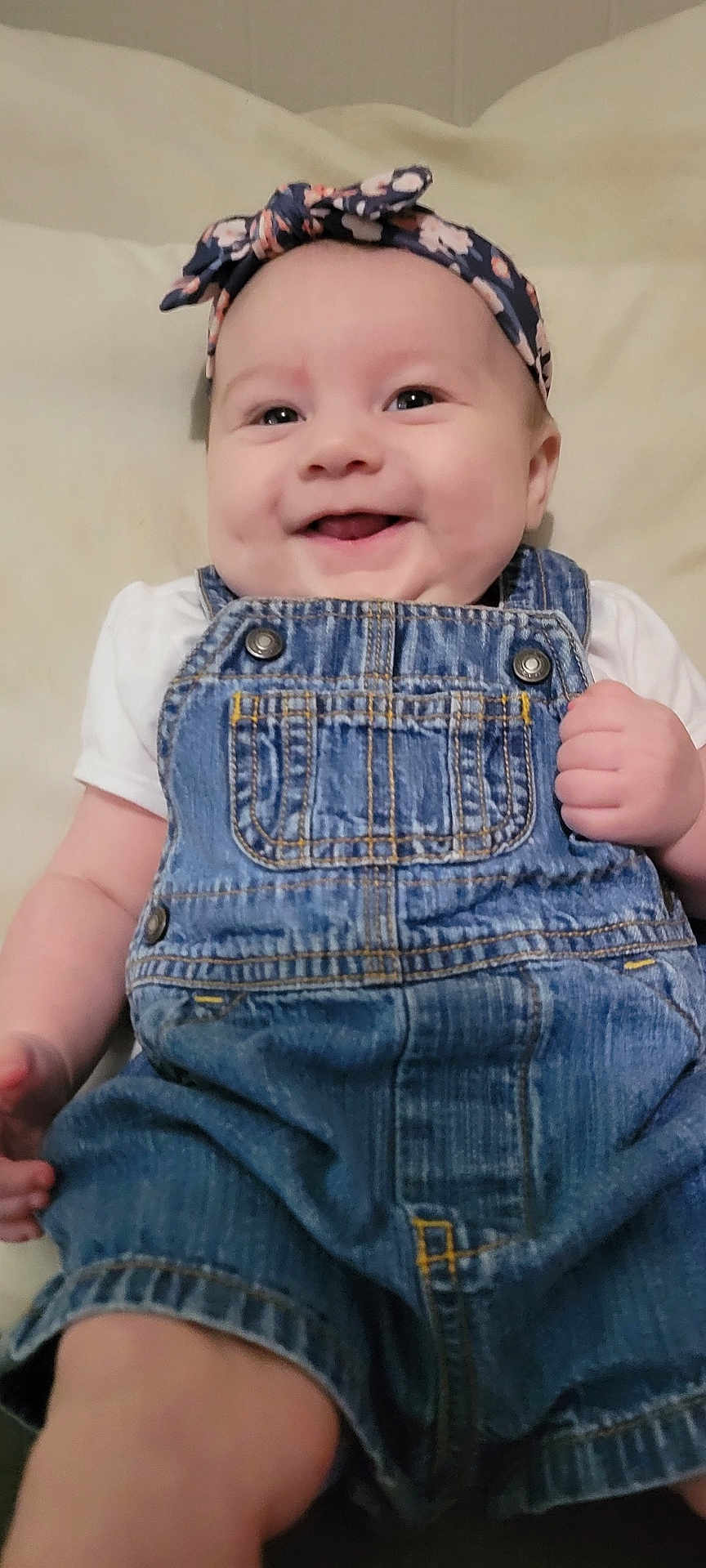 Gabriella joined the competition — help win amazing prizes! baby, denim_overalls, headband, smile, happy, infant, cute, clothing, child, portrait, skin, hand, face, eyes, cheeks, indoors, fabric, soft, background, lying_down