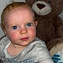 baby, child, teddy_bear, plush_toy, blue_eyes, pajamas, hand, face, indoor, soft_toy, cute, portrait, infant, person, toy, childhood, smiling, skin, baby_clothes, close_up