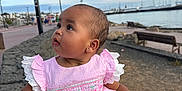 Ophelia is registered to the contest to win money with this photo: baby, child, dress, pink, frills, earrings, hand, stone_wall, waterfront, sky, clouds, bench, boats, promenade, outdoor, portrait, curious, support, person, seaside
