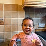 Ophelia joined the competition — help win amazing prizes! bread, child, curly_hair, cute, face, floral_pattern, food, hand, happy, high_chair, indoors, kitchen, meal, person, pink_shirt, smiling, tile_wall, toddler, wooden_cabinet, young