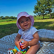 Ophelia is registered to the contest to win money with this photo: baby, blanket, blue_sky, child, cute, daylight, foot, grass, happy, infant, nature, outdoor, park, playing, sitting, smiling, summer, sunhat, toy, trees