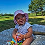 baby, blanket, blue_sky, child, cute, daylight, foot, grass, happy, infant, nature, outdoor, park, playing, sitting, smiling, summer, sunhat, toy, trees