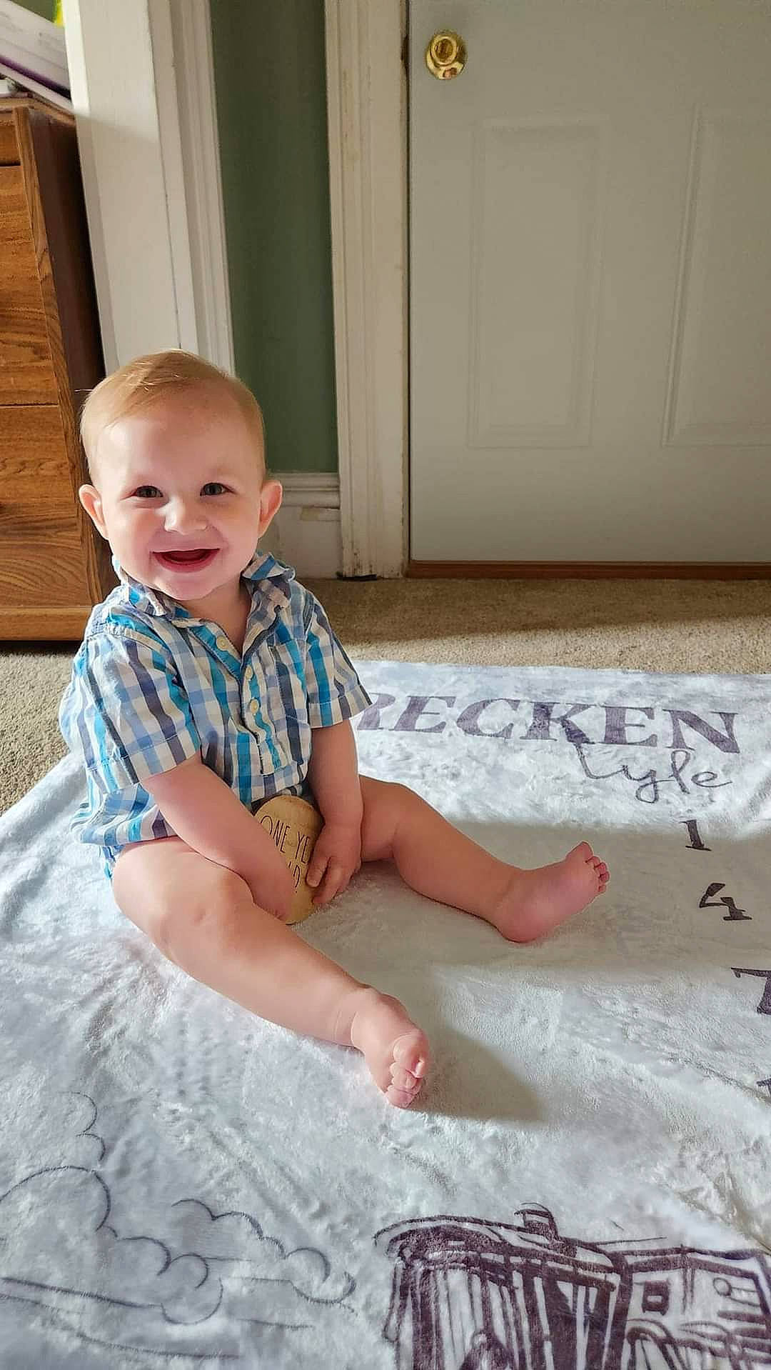 Brecken is registered to the contest to win money with this photo: baby, baby_toddler_clothing, child, comfort, door, dress, floor, flooring, fun, happy, hardwood, human_leg, joy, linens, pattern, person, sitting, sleeve, smile, t_shirt